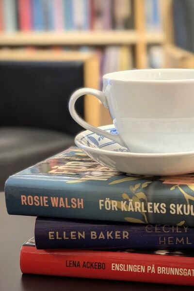 Kaffekopp på fat som står på en bokstapel i biblioteket